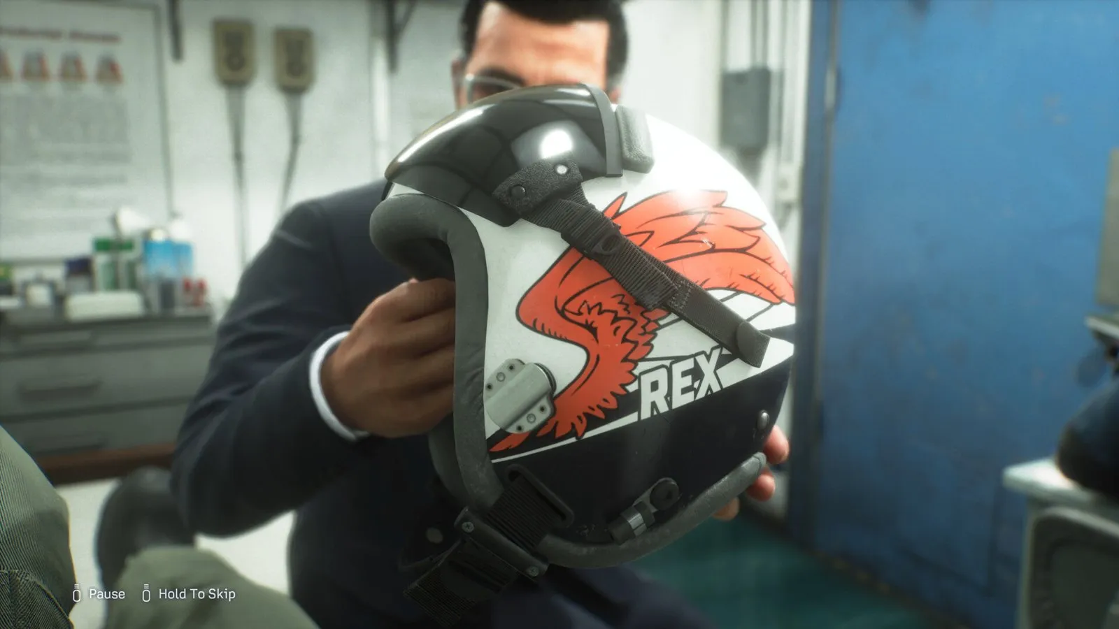 Un hombre sostiene un casco de piloto con un emblema naranja en ACE COMBAT 8: Wings of Theve
