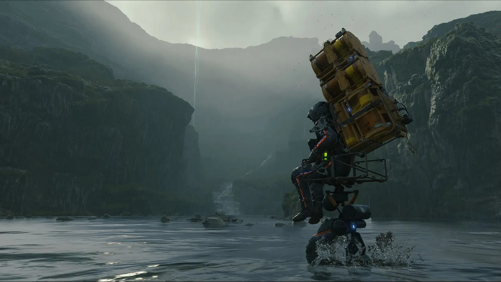 Sam cruza un río con el agua hasta la cintura cargado con una torre de cajas amarillas en Death Stranding Director's Cut