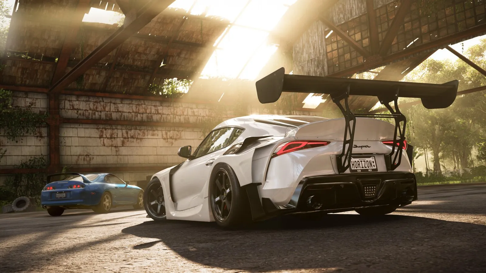 Un Toyota Supra blanco con alerón en un hangar al atardecer en Forza Horizon 5