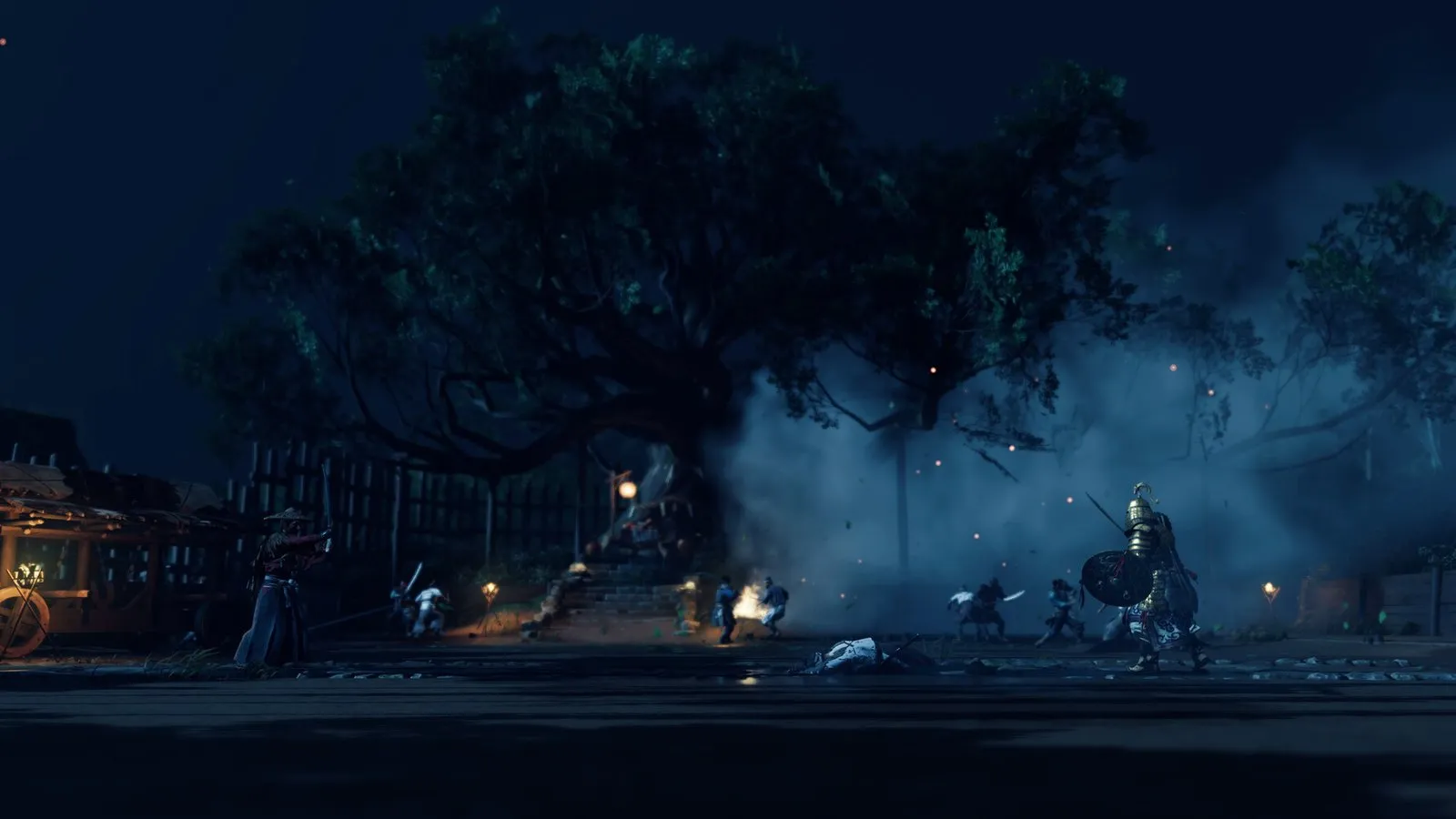 Jin Sakai combate a varios mongoles bajo un gran árbol en una aldea nocturna en Ghost of Tsushima Director's Cut