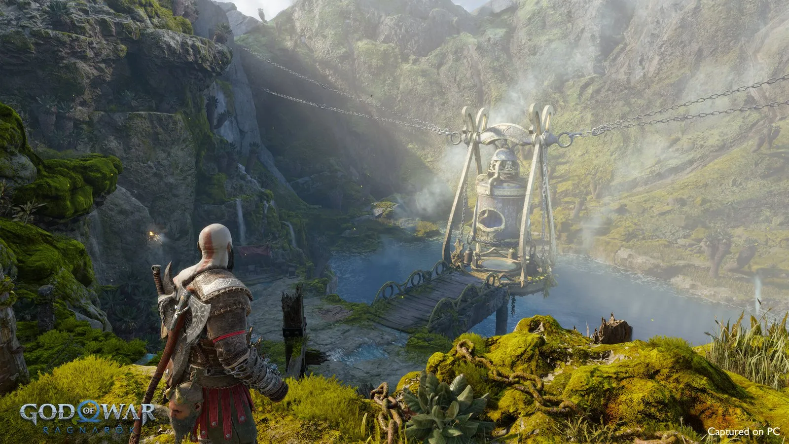 Kratos y Atreus contemplan un puente de cuerdas en un valle verde en God of War Ragnarök