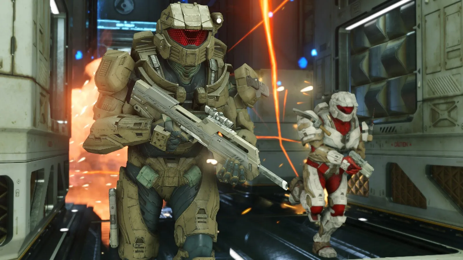 Dos Spartans con rifles de asalto avanzan por un pasillo mientras estalla una explosión en Halo Infinite