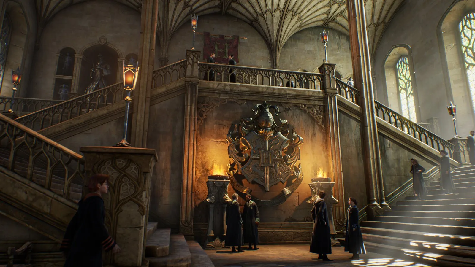 Alumnos con túnica recorren la gran escalera de Hogwarts junto al escudo del colegio en Hogwarts Legacy