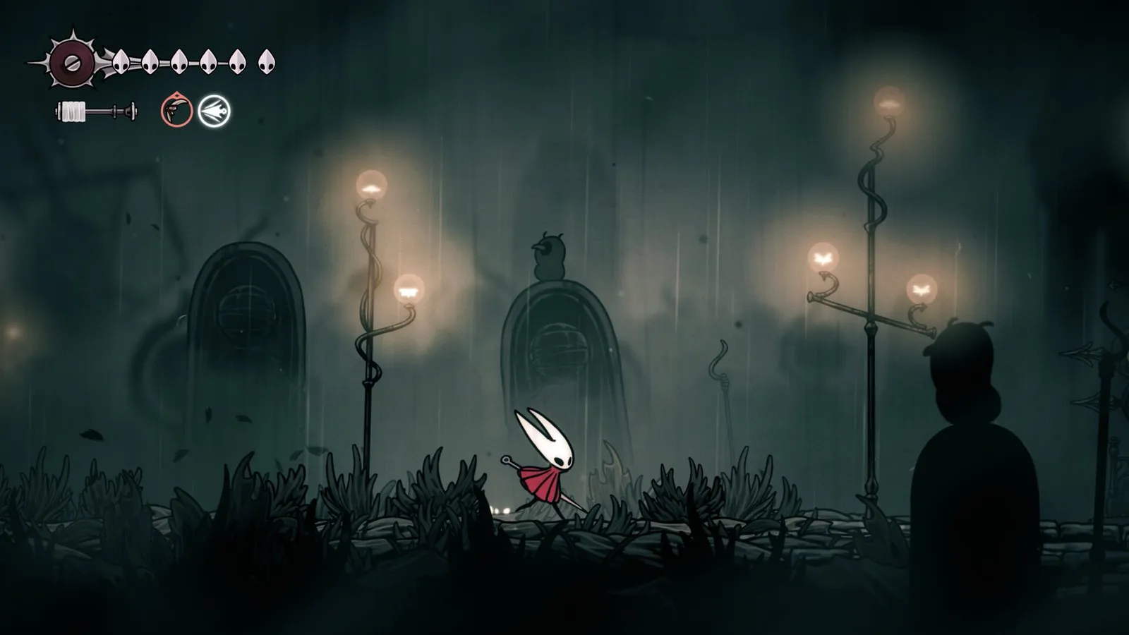 Hornet, pequeña bajo faroles encendidos, camina por una ciudad en ruinas bajo la lluvia en Hollow Knight: Silksong