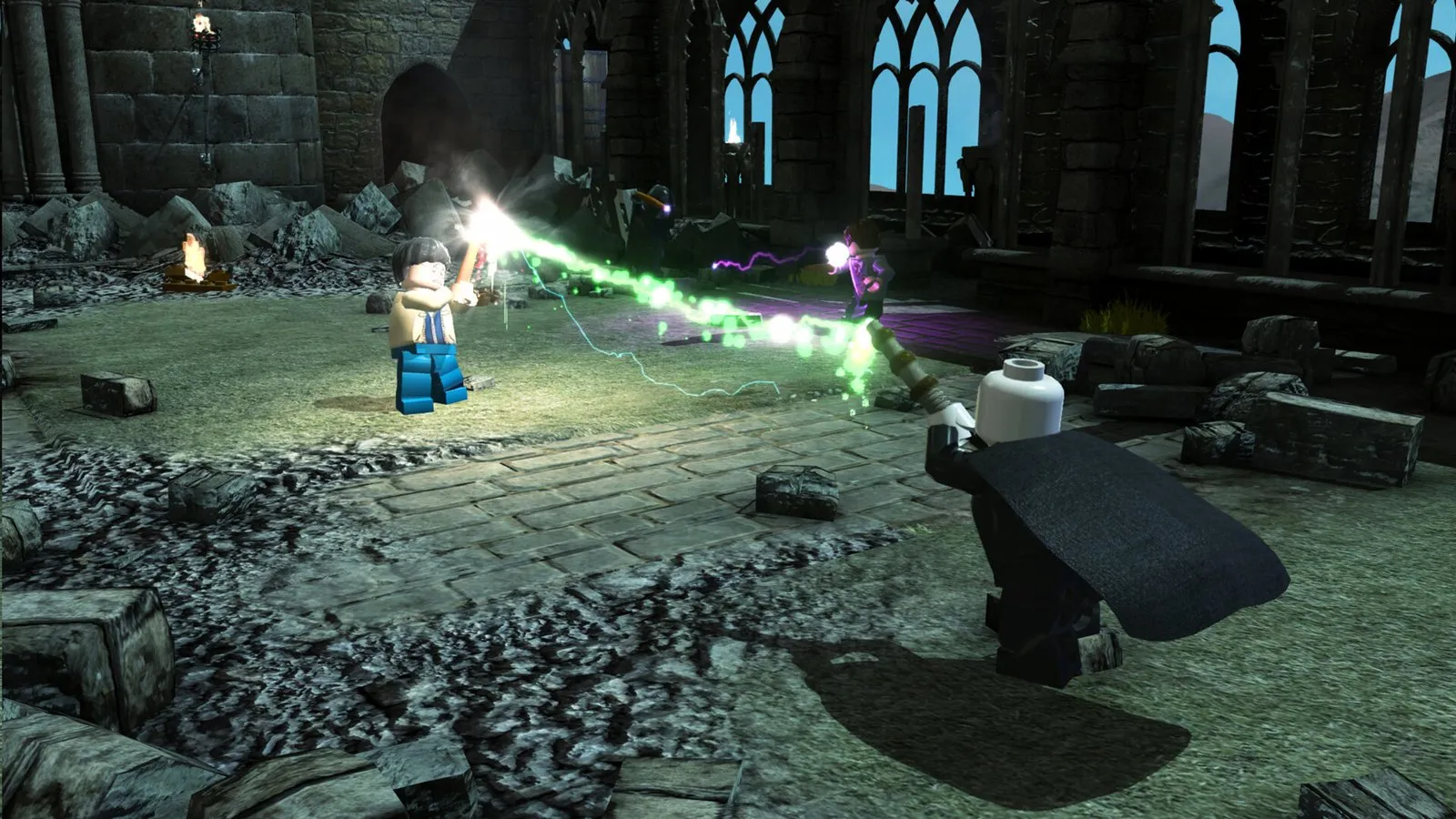 Dos figuras LEGO se lanzan hechizos de colores en un patio de Hogwarts de noche en LEGO Harry Potter Collection