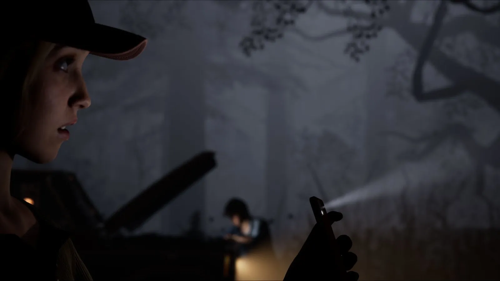 Una joven con gorra observa en la oscuridad mientras otro personaje ilumina el bosque con una linterna en The Quarry