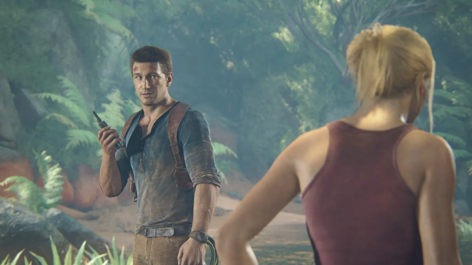 Nathan Drake con un walkie-talkie y Elena de espaldas en una jungla en Uncharted: Colección Legado de los Ladrones