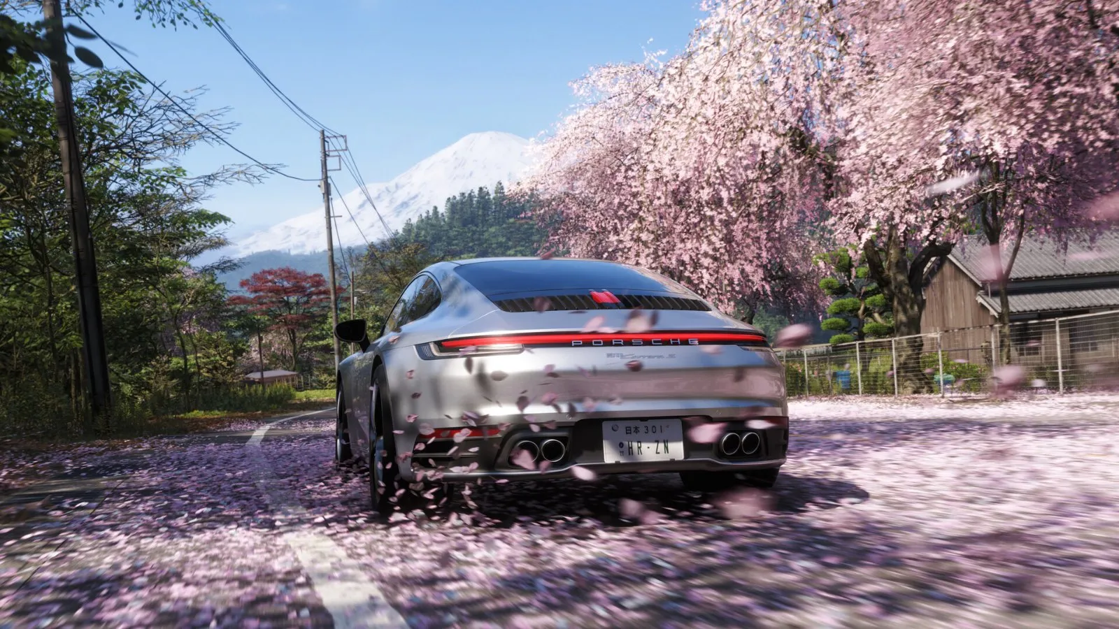 Un Porsche plateado circula por una calle cubierta de flores de cerezo con el monte Fuji al fondo en Forza Horizon 6